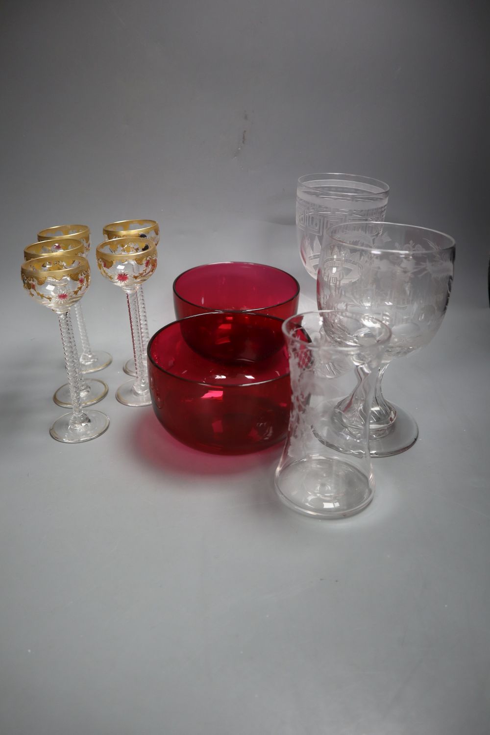 A pair of cranberry rinsers, four airtwist gilt decorated glasses, a Greek key patterned wine glass, an etched glass with motto and a v